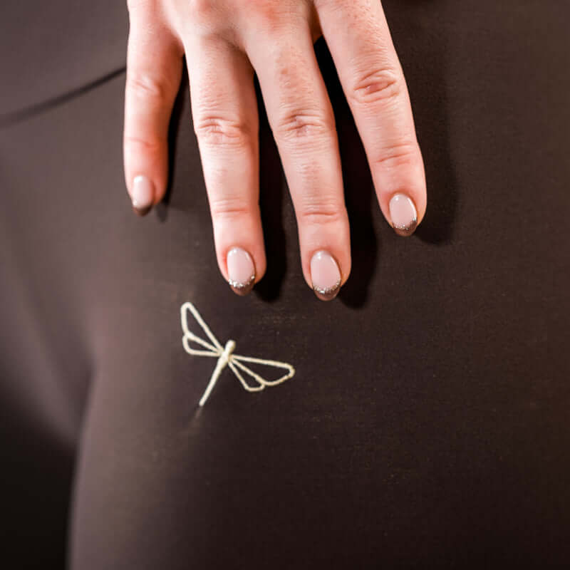 Close-up of pole dance clothing featuring dragonfly embroidery on pole shorts, showcasing stylish pole wear.