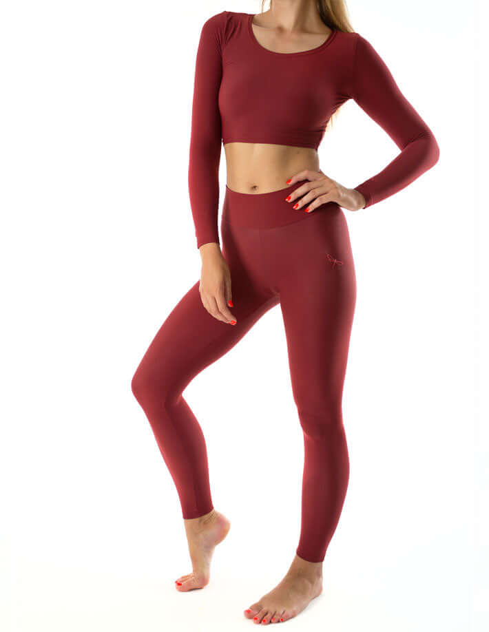 Model wearing mid rise leggings and a matching crop top in burgundy, showcasing comfort and style for yoga and fitness.